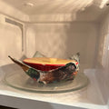 Ceramic bowl in a cozy placed inside of a microwave.