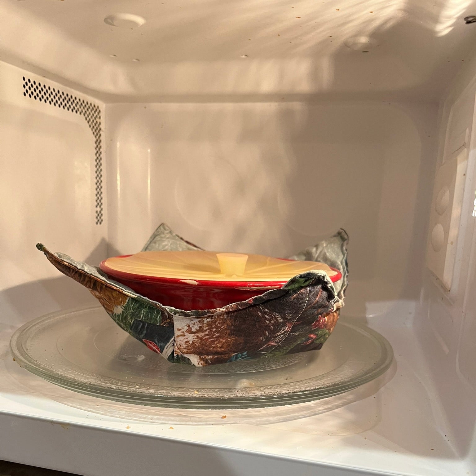 Ceramic bowl in a cozy placed inside of a microwave.