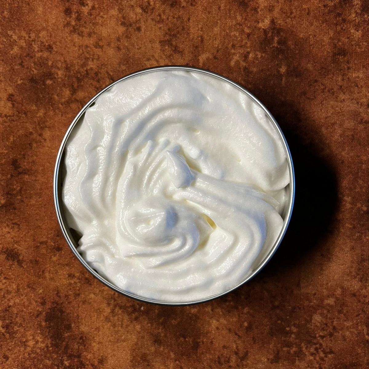 A round tin of whipped tallow body butter without the lid.